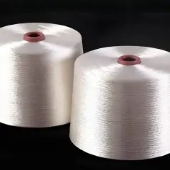 Zwei Spulen mit glänzendem, weißem Rayon-Garn. Dieses Garn ist ideal, um Stoffe zu nähen, die sich weich anfühlen und gut fallen, wie z.B. Kleider oder Blusen.