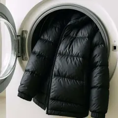 Schwarze Daunenjacke in einer Waschmaschine. Achten Sie auf die richtige Temperatur beim **daunen waschen temperatur**, damit die Füllung nicht beschädigt wird.