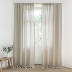 Helle Leinen Gardinen hängen vor einem Fenster. Sie sind frisch gewaschen und duften nach Sommer.