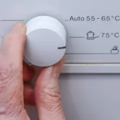 Hand dreht Regler an Waschmaschine. Das 30 Grad Programm ist nicht sichtbar, aber 40°C und 50°C sind wählbar.