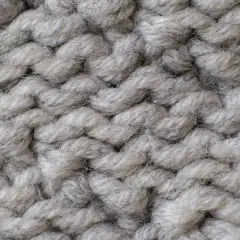 Nahaufnahme einer dicken, grauen Stricktextur. Die Garnstränge sind grob und flauschig, perfekt für einen gemütlichen **Wolle trockner**.
