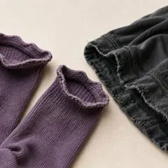 Lila Socken mit Rüschenrand und dunkle Hose. Elasthan Nachteile: Der Stoff kann ausleiern und die Nähte fransen.