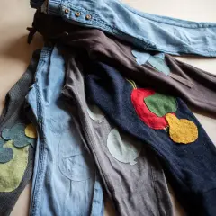 Bunte Flicken auf Kinderhosen. Ein **Knie** mit einem roten Apfel, daneben ein **Knie** mit Ballons. Liebevoll gestaltete **Hosen flicken**.