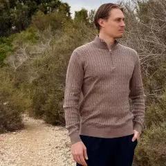 Mann in braunem Zopfmuster-Pullover aus Kaschmir, der in der Natur steht. Ist Kaschmir warm? Ja, dieser Pullover beweist es.