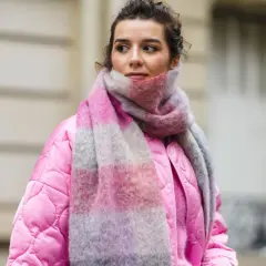 Frau mit pinker Jacke und gestreiftem Schal, inspiriert, einen Schal selber machen.