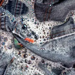 Jeans schleudern in schaumigem Wasser. Bunte Seifenblasen tanzen auf dem Denim.