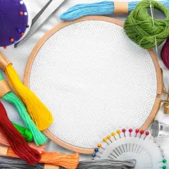 Buntes Stickgarn, Nadeln, Schere, Fingerhut und Stickrahmen – alles, was man zum Sticken braucht, liegt bereit für kreative Projekte.