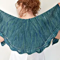 Frau hält ein wunderschönes, blau-grün meliertes **Tuch stricken** mit zarten Lochmustern am Rand.