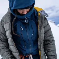 Person in Daunenjacke im Schnee. Die Daunenjacke waschen ist wichtig, um sie warm zu halten.