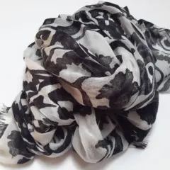 Ein leicht zerknitterter Schal aus Polyester-Plastik mit einem auffälligen schwarz-weißen Blumenmuster.