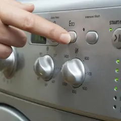 Finger drückt "Eco"-Taste. Frage: wie lange dauert waschmaschine 60 grad? Das Display zeigt "FIT".