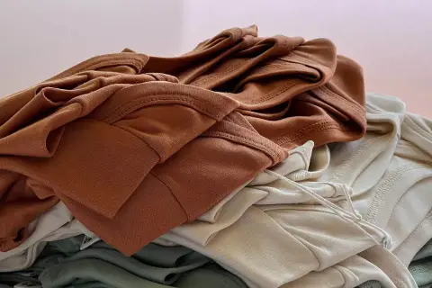Stapel weicher Stoffe in Erdtönen. Die Falten und Nähte zeigen die Textur, die bei Tencel Nachteile wie Knitteranfälligkeit haben kann.