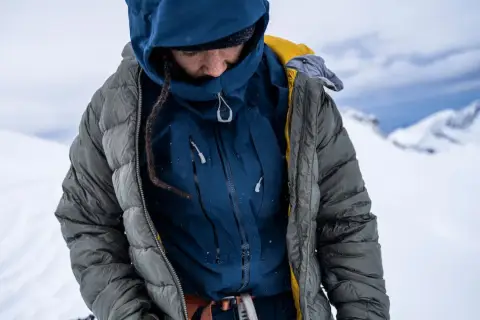 Person in Daunenjacke im Schnee. Die Daunenjacke waschen ist wichtig, um sie warm zu halten.