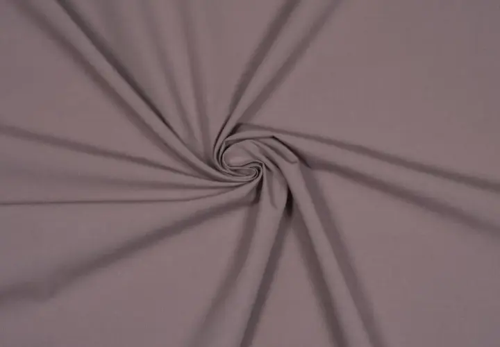 Ein glatter, taupefarbener Stoff, der sich zu einer Spirale dreht. Dies ist ein Beispiel für Popeline, ein dicht gewebtes Baumwollmaterial.