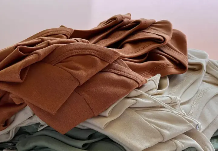 Stapel weicher Stoffe in Erdtönen. Die Falten und Nähte zeigen die Textur, die bei Tencel Nachteile wie Knitteranfälligkeit haben kann.