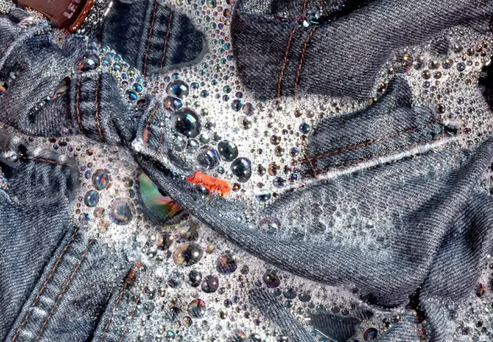Jeans schleudern in schaumigem Wasser. Bunte Seifenblasen tanzen auf dem Denim.