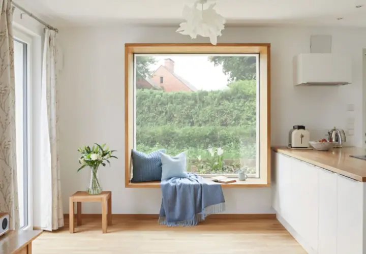 Gemütliche Sitzecke am Fenster ohne Fensterbank: Kissen, Decke und Buch laden zum Verweilen ein.