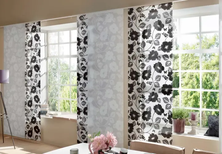 Schiebegardine kurz mit floralem Muster in Schwarz und Weiß. Helle Paneele mit zarten Blüten und dunklere mit kräftigen Blumen und Schmetterlingen schmücken das Fenster.