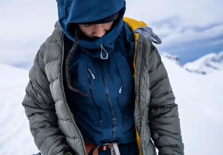 Person in Daunenjacke im Schnee. Die Daunenjacke waschen ist wichtig, um sie warm zu halten.