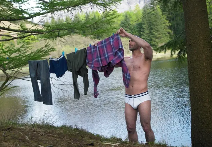 Mann hängt Wäsche auf, darunter auch eine **Boxershorts**, zum Trocknen am Seeufer.