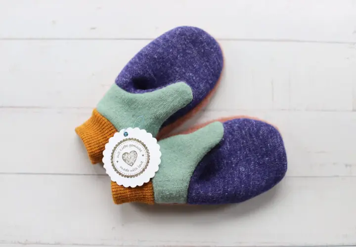 Bunte Fäustlinge mit einem "mit Liebe gemacht"-Anhänger. Ideal für DIY-Projekte, hier gibt es handschuhe schnittmuster kostenlos.