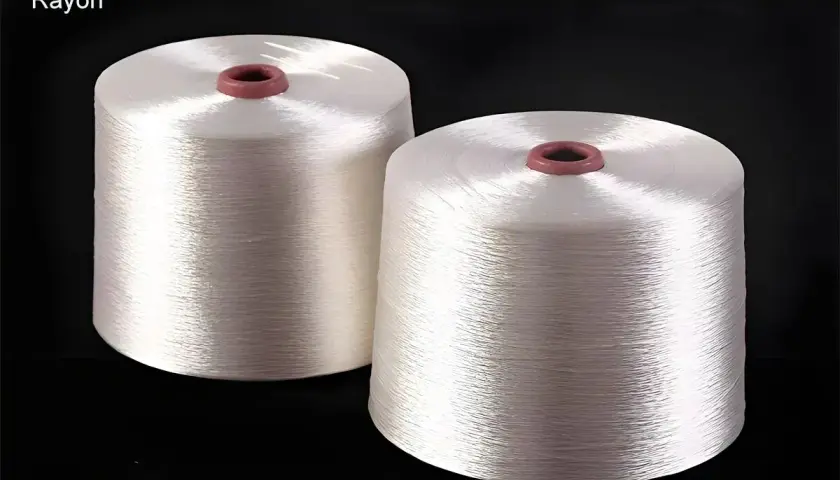 Zwei Spulen mit glänzendem, weißem Rayon-Garn. Dieses Garn ist ideal, um Stoffe zu nähen, die sich weich anfühlen und gut fallen, wie z.B. Kleider oder Blusen.