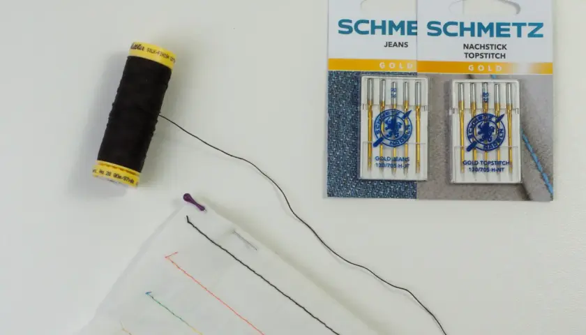 Schwarzer faden zum reparieren von kleidung, Nadeln und Stoff mit bunten Stichproben.
