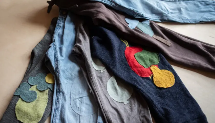 Bunte Flicken auf Kinderhosen. Ein **Knie** mit einem roten Apfel, daneben ein **Knie** mit Ballons. Liebevoll gestaltete **Hosen flicken**.