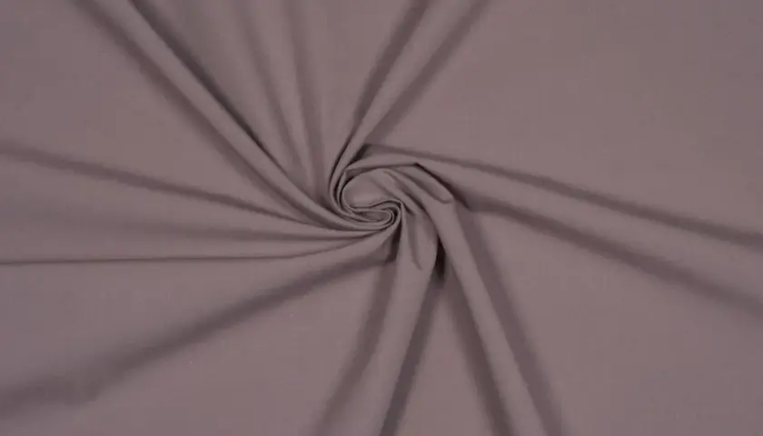 Ein glatter, taupefarbener Stoff, der sich zu einer Spirale dreht. Dies ist ein Beispiel für Popeline, ein dicht gewebtes Baumwollmaterial.
