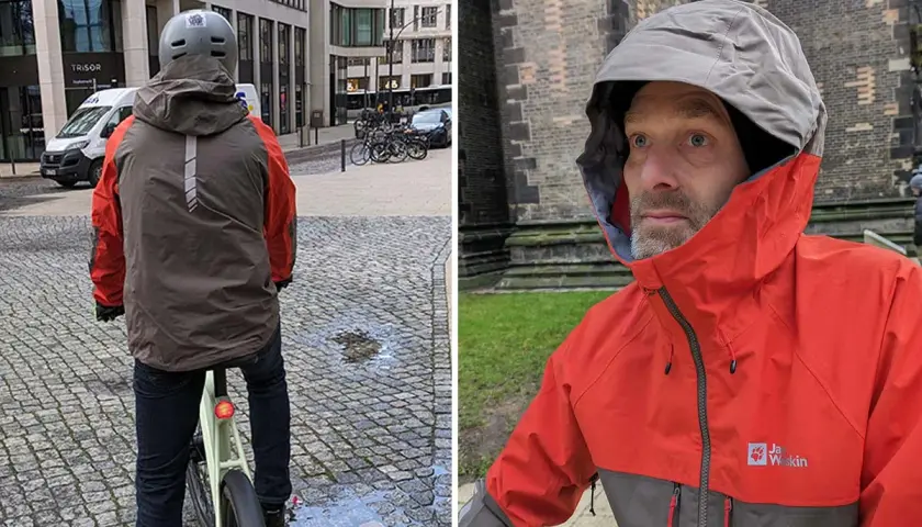 Mann mit Helm auf Fahrrad, trägt eine zweifarbige Funktionsjacke. Nahaufnahme des Mannes in der Jacke mit Kapuze.