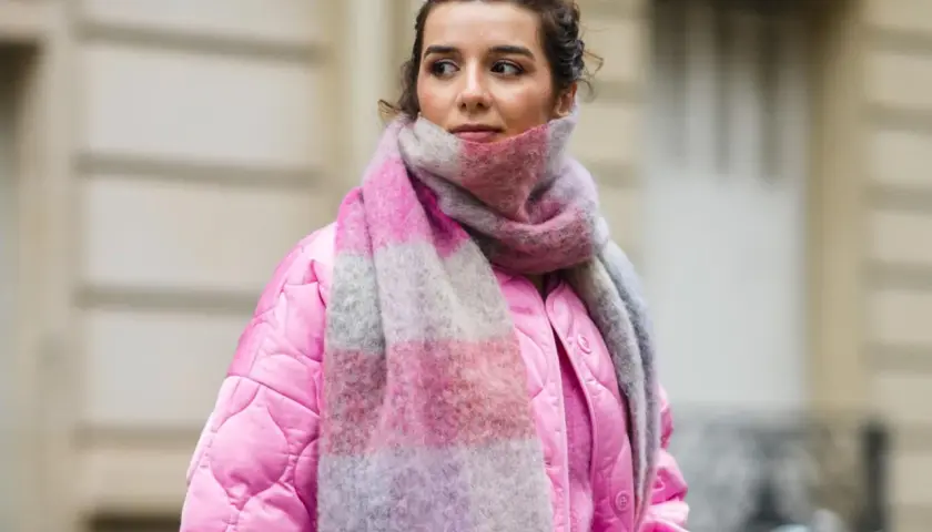 Frau mit pinker Jacke und gestreiftem Schal, inspiriert, einen Schal selber machen.