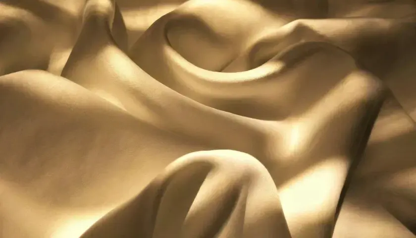Sanfter Glanz auf gewaschenem Satin. Die Falten des Stoffes werfen weiche Schatten und erzeugen ein Gefühl von Luxus und Ruhe.