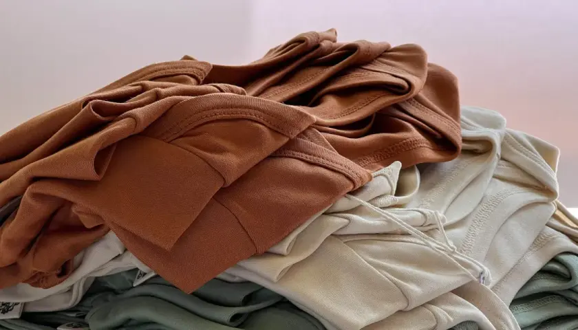 Stapel weicher Stoffe in Erdtönen. Die Falten und Nähte zeigen die Textur, die bei Tencel Nachteile wie Knitteranfälligkeit haben kann.