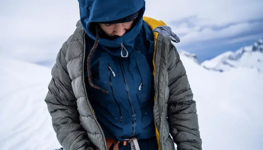 Person in Daunenjacke im Schnee. Die Daunenjacke waschen ist wichtig, um sie warm zu halten.
