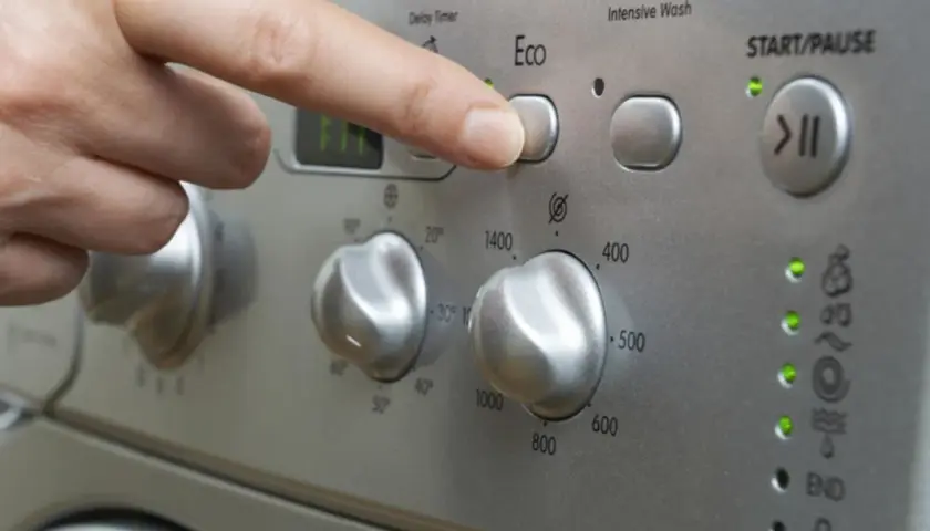 Finger drückt "Eco"-Taste. Frage: wie lange dauert waschmaschine 60 grad? Das Display zeigt "FIT".