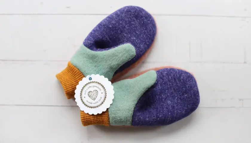 Bunte Fäustlinge mit einem "mit Liebe gemacht"-Anhänger. Ideal für DIY-Projekte, hier gibt es handschuhe schnittmuster kostenlos.