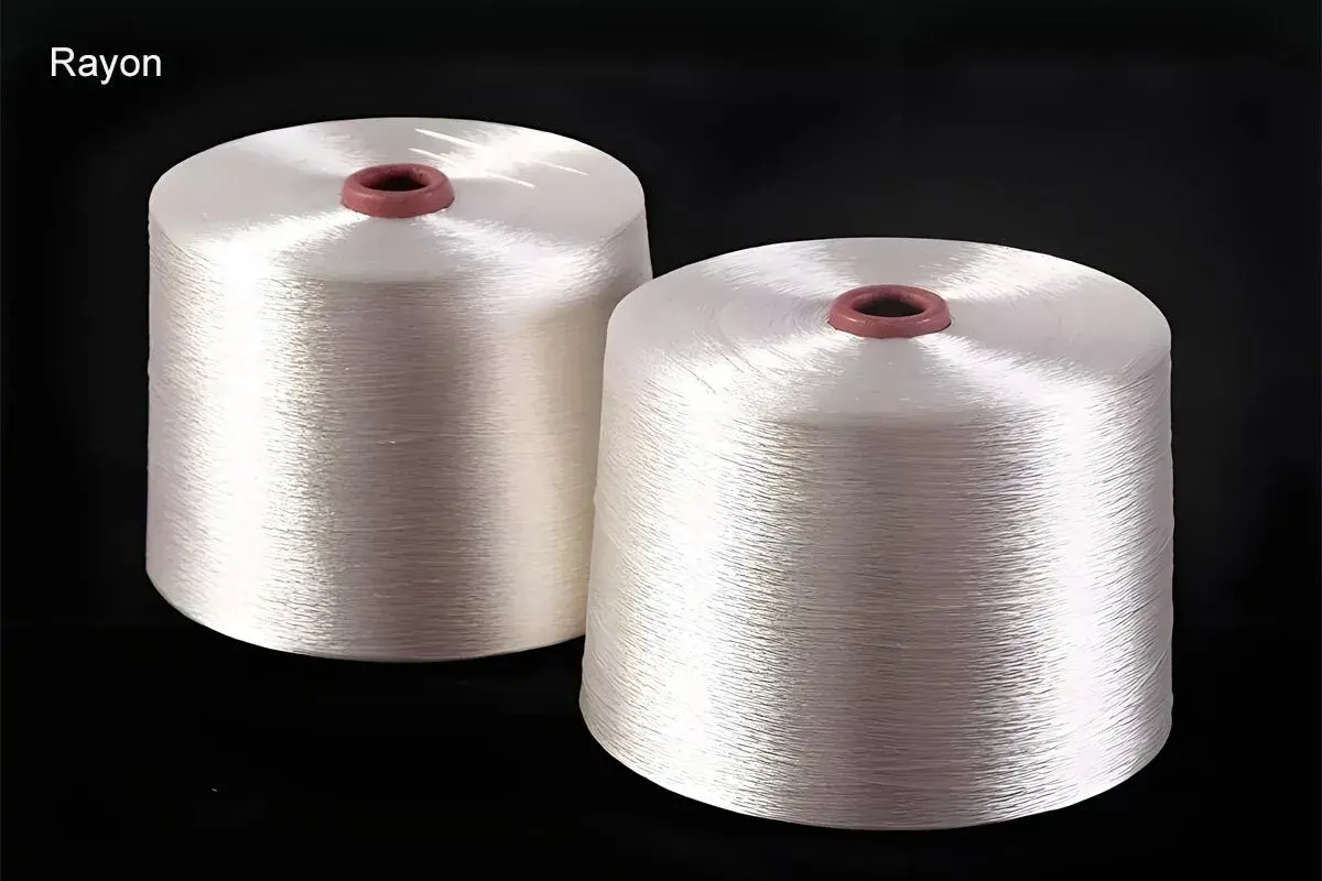 Zwei Spulen mit glänzendem, weißem Rayon-Garn. Dieses Garn ist ideal, um Stoffe zu nähen, die sich weich anfühlen und gut fallen, wie z.B. Kleider oder Blusen.