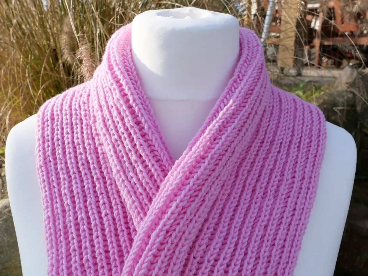 Ein rosa gestrickter Schal mit einem einfachen Rippenmuster, perfekt für Anfänger.