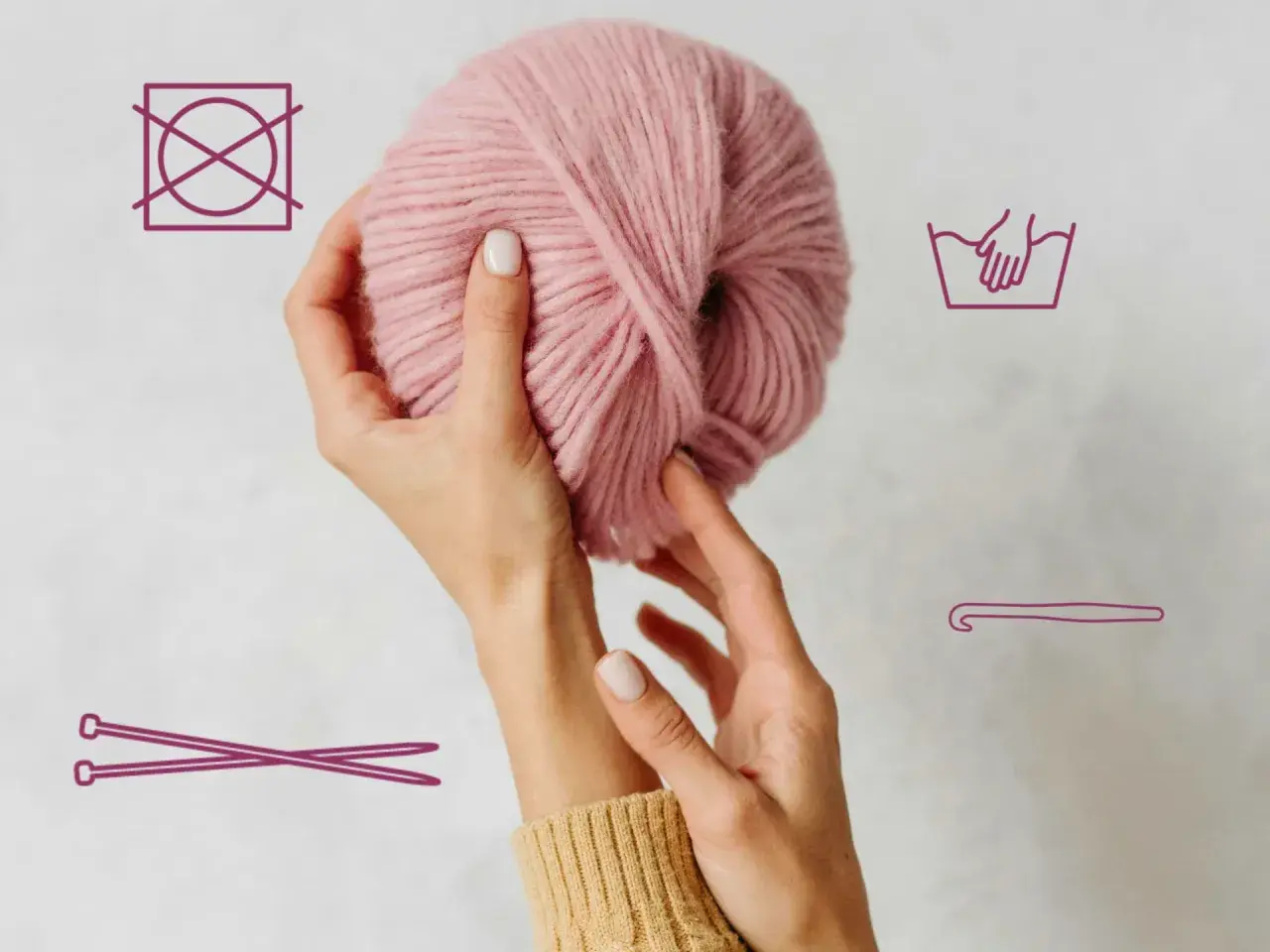 Hände halten rosafarbene Wolle. Symbole zeigen Handwäsche, kein Trocknen und Stricknadeln/Häkelnadel.