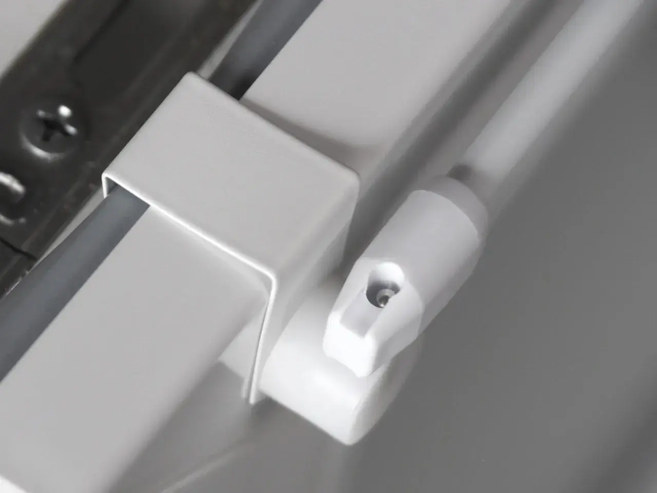 Detailaufnahme einer weißen Gardinenstange, die nur an den Seiten befestigt ist. Ein Teil der Halterung ist sichtbar.