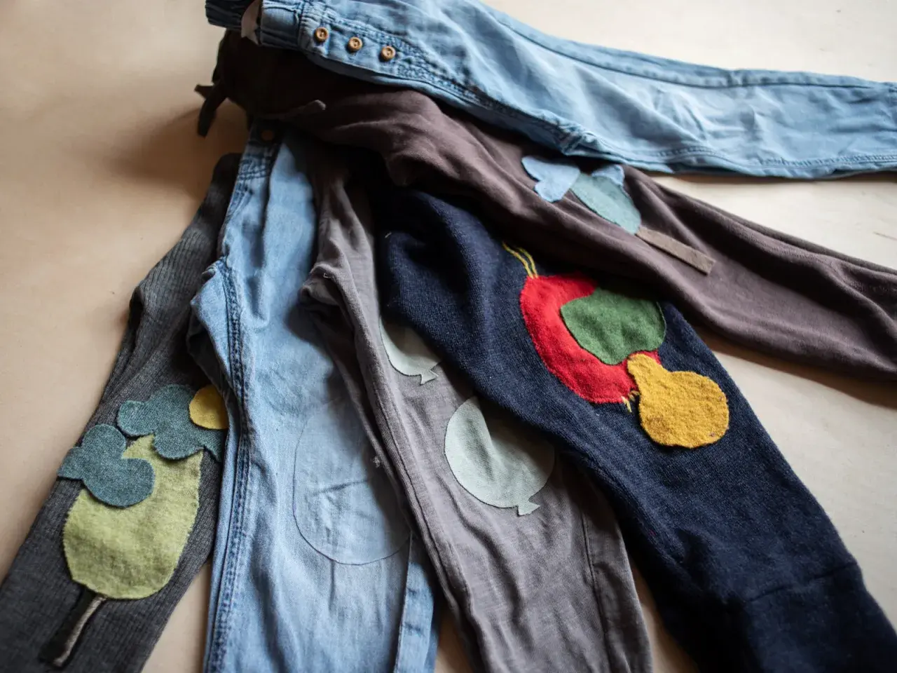 Bunte Flicken auf Kinderhosen. Ein **Knie** mit einem roten Apfel, daneben ein **Knie** mit Ballons. Liebevoll gestaltete **Hosen flicken**.