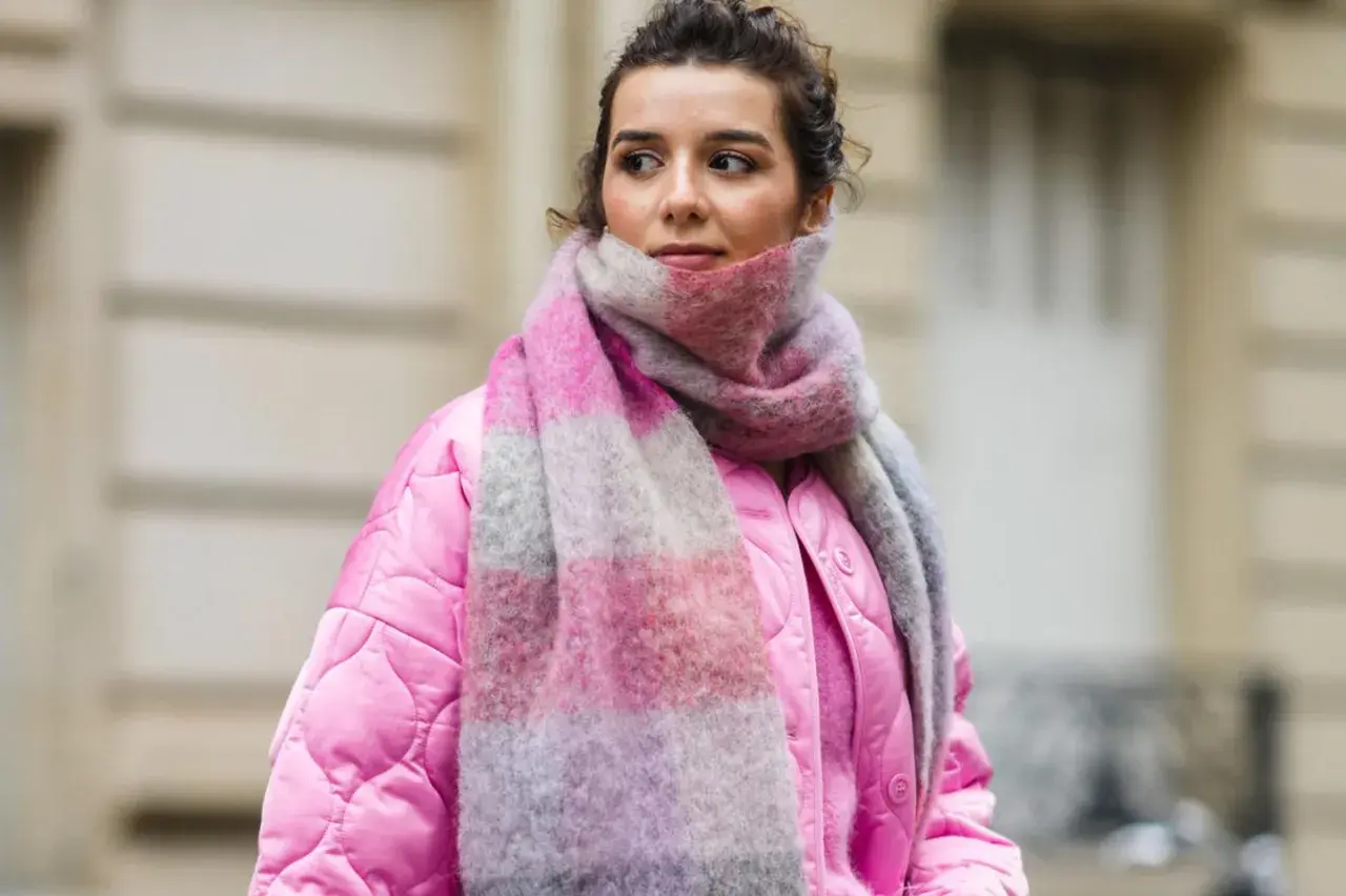 Frau mit pinker Jacke und gestreiftem Schal, inspiriert, einen Schal selber machen.