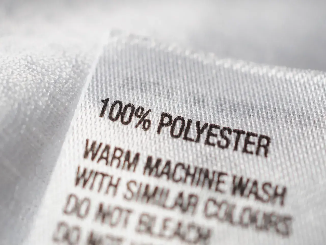 Etikett zeigt: 100% Polyester. Maschinenwäsche warm mit ähnlichen Farben. Nicht bleichen.