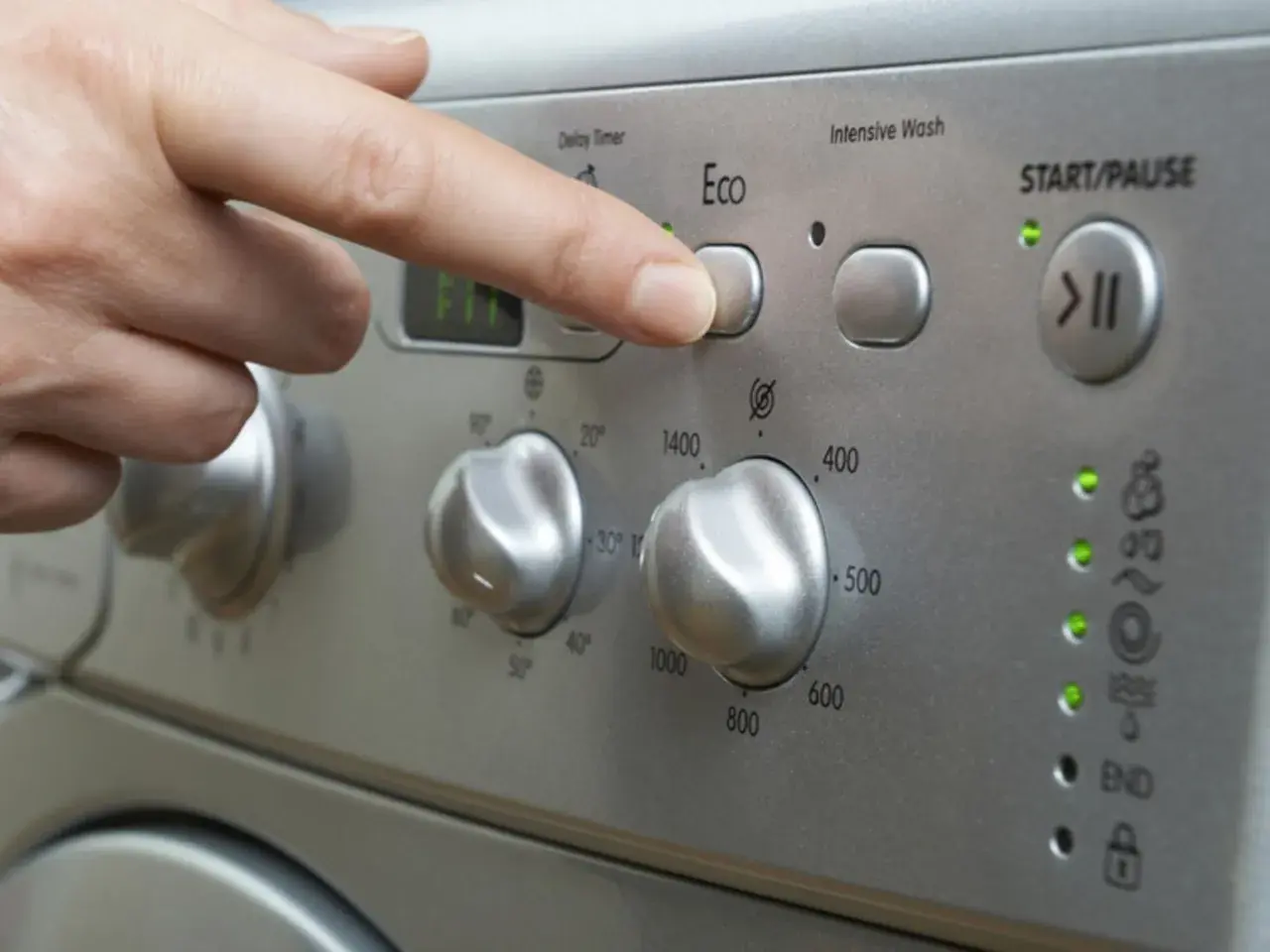 Finger drückt "Eco"-Taste. Frage: wie lange dauert waschmaschine 60 grad? Das Display zeigt "FIT".