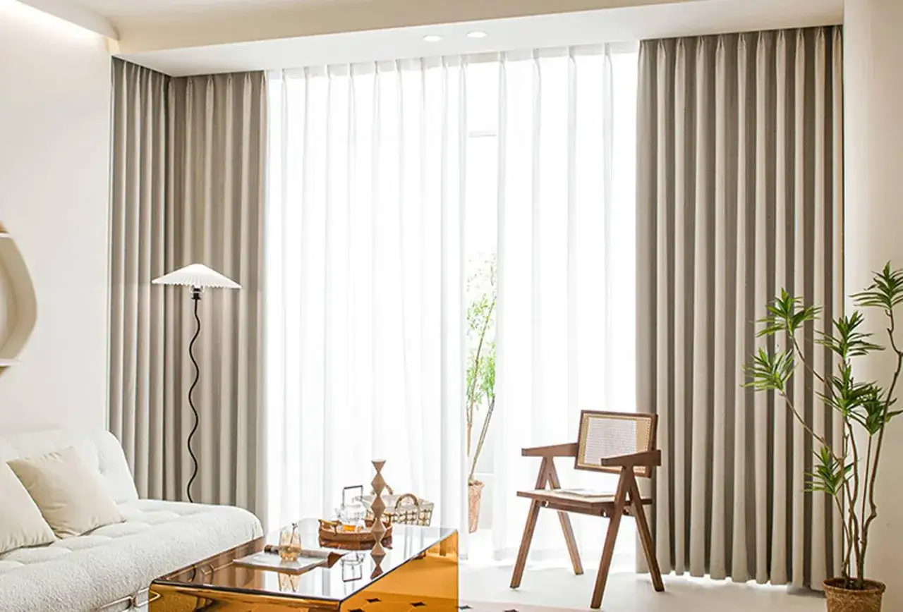 Ein heller Wohnraum mit einem Sofa, einem Couchtisch und einem Stuhl. Der vorhang nur auf einer fensterseite lässt viel Licht herein.