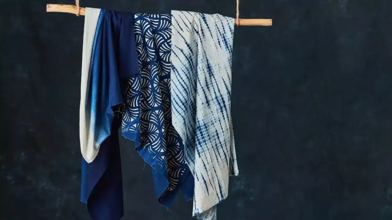 Drei Stoffe h&auml;ngen an einem Holzstab. Einer ist einfarbig dunkelblau, der n&auml;chste hat ein wei&szlig;es Muster auf blauem Grund, der dritte ist wei&szlig; mit blauen Streifen. Viskose Nachteile: empfindlich, knittert leicht.