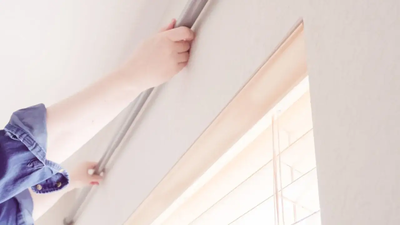 Hände bringen eine Gardinenstange an der Wand an, um einen Vorhang anzubringen.