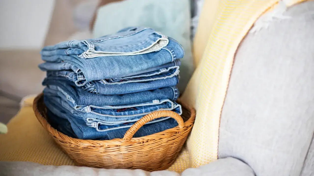 Ein Korb voller ordentlich gefalteter Jeans. Die verschiedenen Blautöne der Jeans schleudern im Licht.