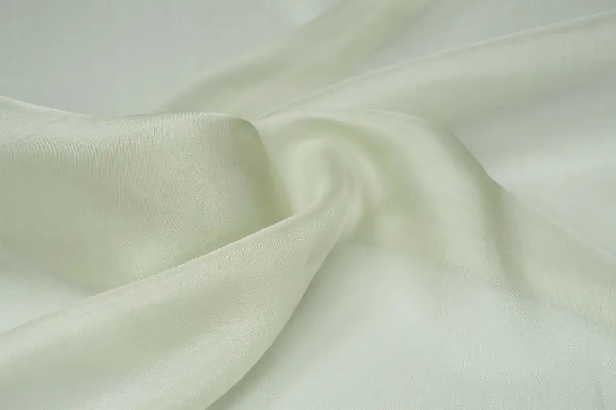 Sanft fallende, cremefarbene Seide trocknen. Das Material schimmert leicht und bildet elegante Falten.