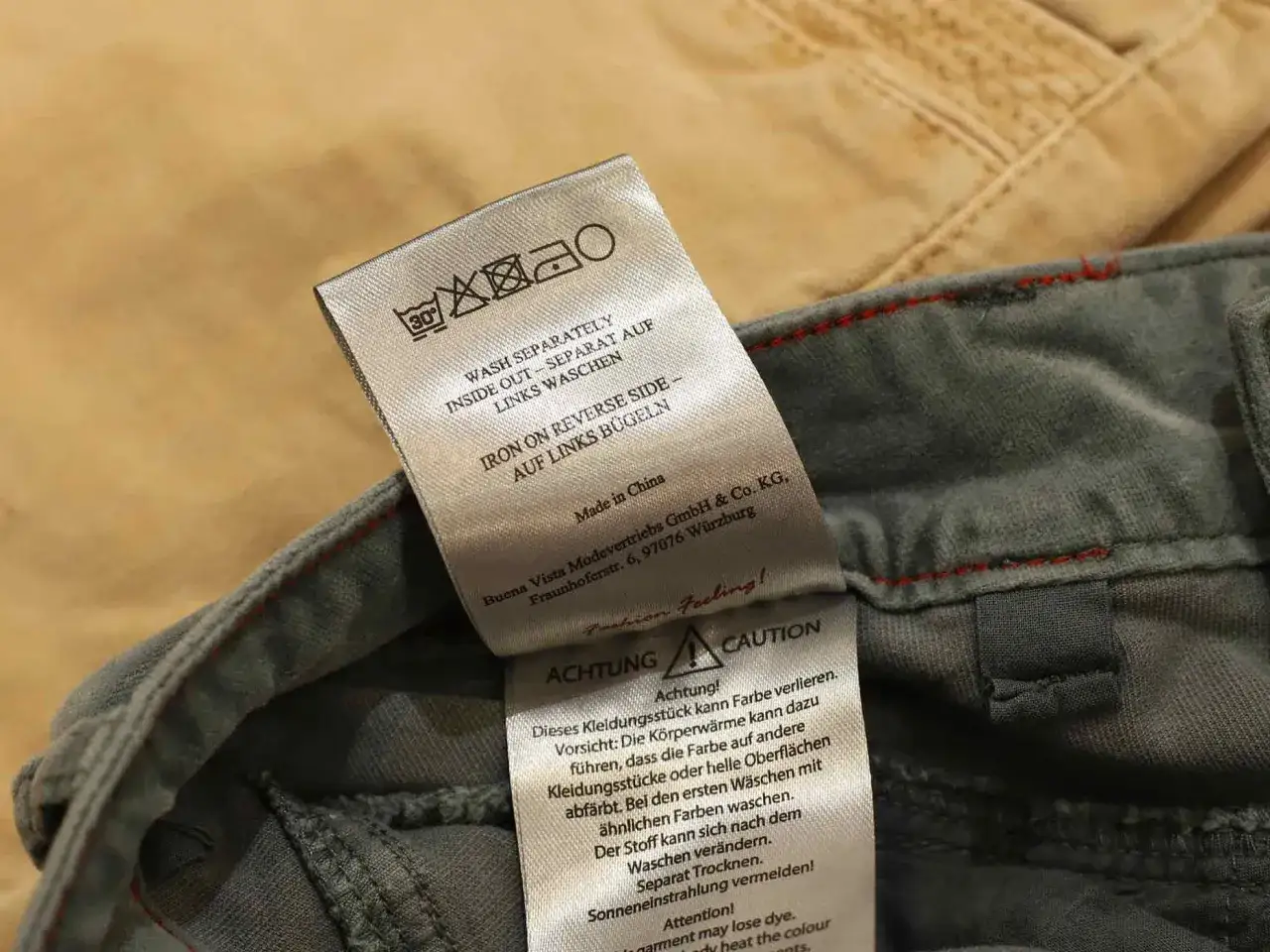 Pflegeetikett zeigt, wie man Jeans richtig waschen: separat, auf links drehen und bei niedriger Temperatur bügeln.